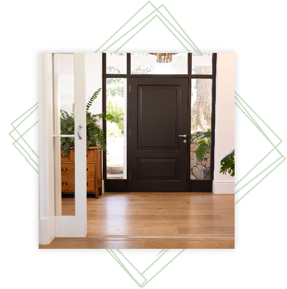 Black door framed by bright greenery indoors