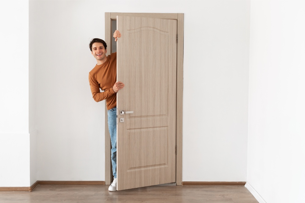Smiling man holding a wooden room door